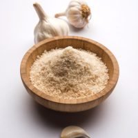 Garlic or Lahsun powder is ground, dehydrated garlic. It's a common seasoning  for pasta, pizza and grilled chicken. Over white background, selective focus