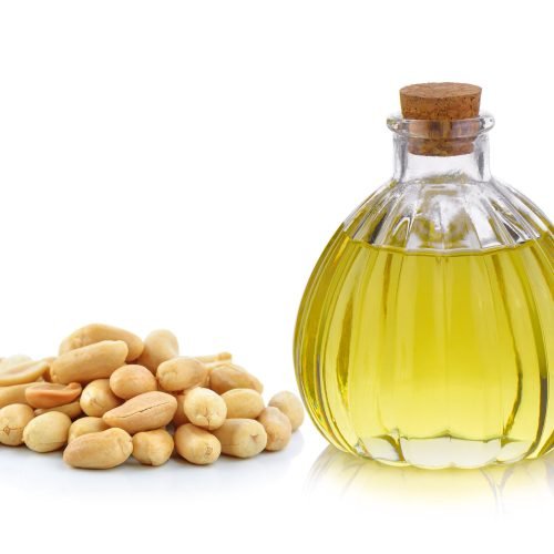 Oil bottle and peanuts on white background